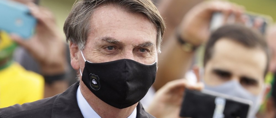 FILE - In this May 25, 2020, file photo, Brazil's President Jair Bolsonaro, wearing a face mask amid the coronavirus pandemic, stands among supporters as he leaves his official residence of Alvorada palace in Brasilia, Brazil. Bolsonaro said Tuesday, July 7, he tested positive for COVID-19 after months of downplaying the virus's severity while deaths mounted rapidly inside the country 